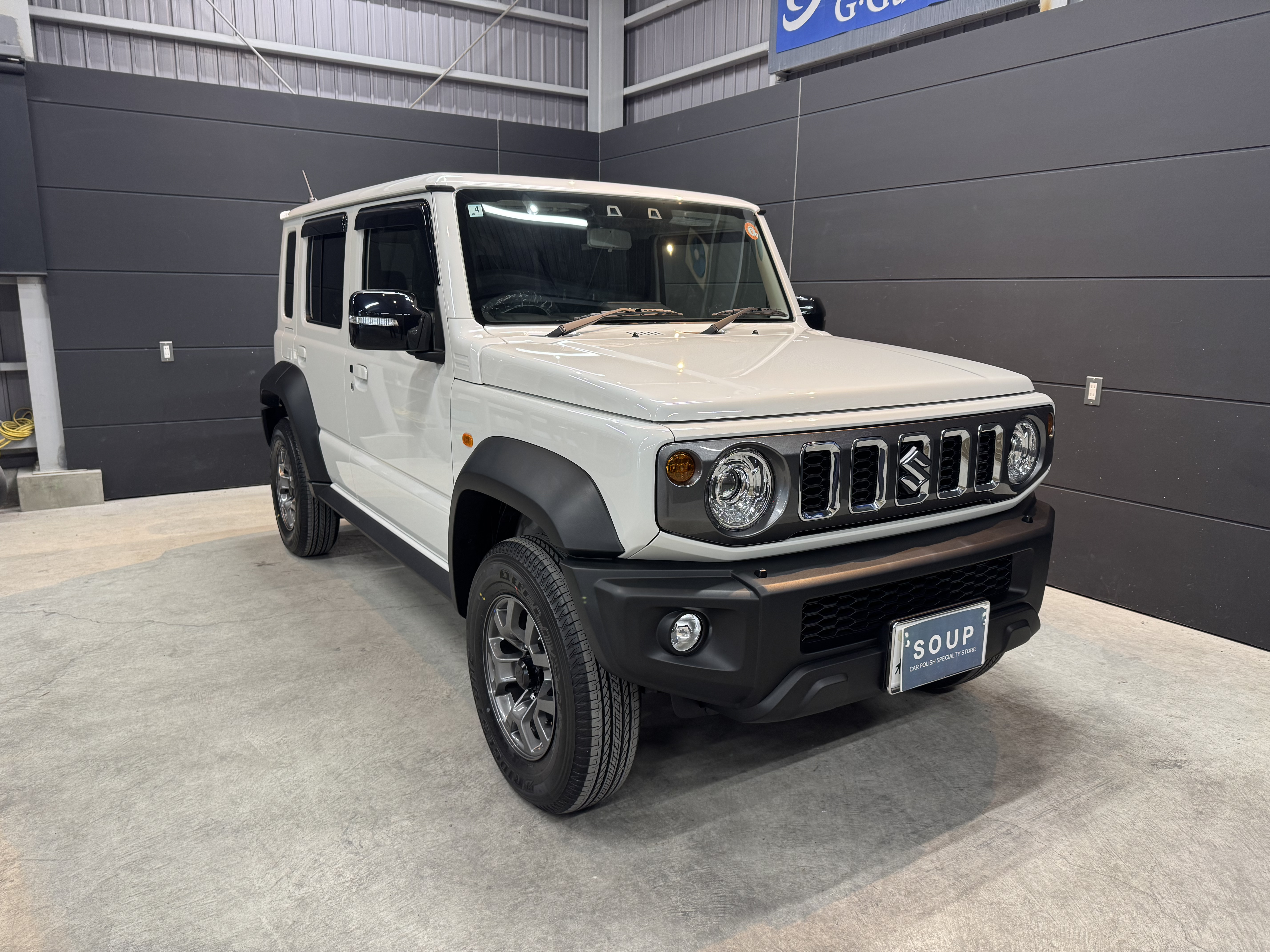 アウトドアシーンに溶け込むスズキ・ジムニー ノマド。無骨なスタイルとタフな足回りが映える一枚。SOUPのセラミックコーティングで自然の中でも存在感を放つ、特別な一台。