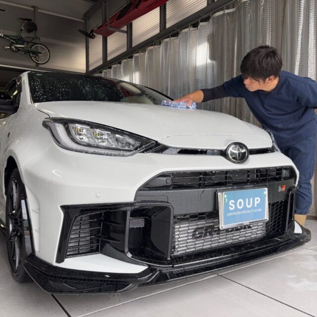 徳島県のカーコーティング専門店SOUPで、新車トヨタ GRヤリス（GXPA16）にSystemX PROセラミックコーティングを施工中の様子。細部洗浄とボディ全体の洗浄工程を丁寧に実施し、艶やかな仕上がりを目指す作業風景。