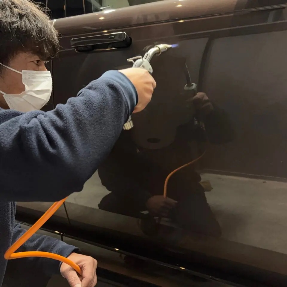 濃色車の側面へガスプライマーを施工するSOUPの施工者