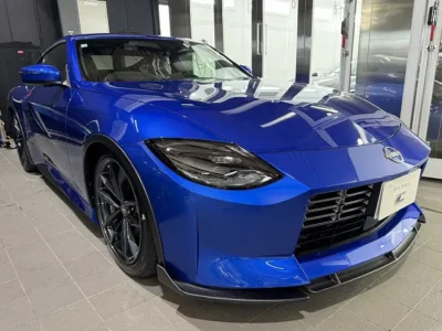 019-1jpg - 徳島のガラスコーティング・セラミックコーティング専門店 スープ Front-left three-quarter view of a bright blue Nissan Z sports car in a showroom, highlighting its aggressive grille, sharp headlights, and sculpted bumper.