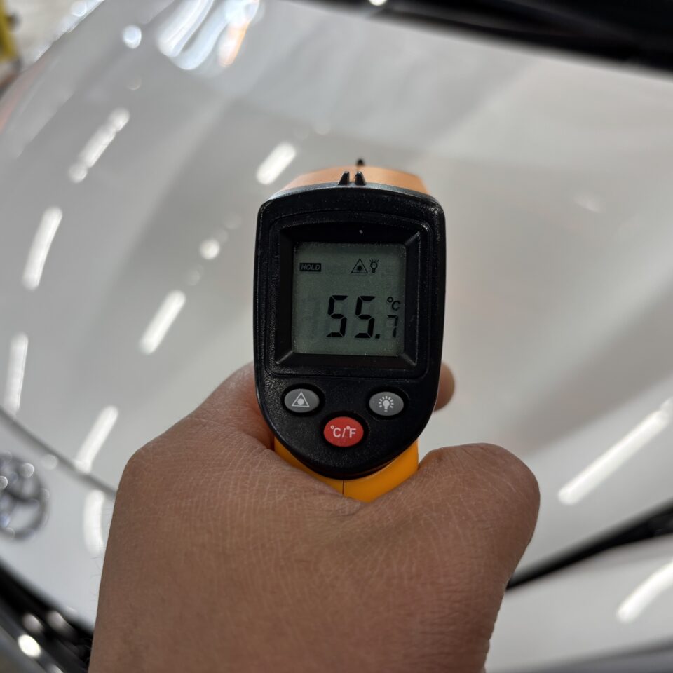SOUP施工ブース・トヨタ新車MXPK16アクアのボンネット表面にIRサーモを当てた一次データ55.7℃。徳島のセラミックコーティング硬化温度の実測値