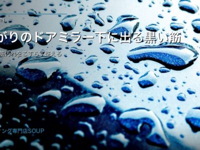 雨上がりの黒い車のドアミラー下に残る水筋を柔らかいクロスで確認するコーティング車ケアイメージ