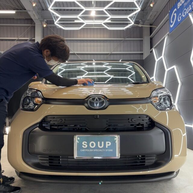 新車 トヨタ MXPL10 シエンタへ、徳島県三好市のカーコーティング専門店SOUPがG.Guardガラスコーティング専用TOPコートを手塗り施工。細部まで丁寧に塗り込むことで、ガラス被膜表面の滑らかさと艶感を向上させ、撥水性能・防汚性能をさらに高次元へ引き上げます。普段のお手入れもしやすくなり、美しい状態を長期間維持できるプレミアムな仕上がりを実現します。