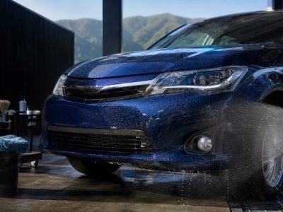 高速道路走行後の虫汚れを水でやさしく流している青いコーティング施工車